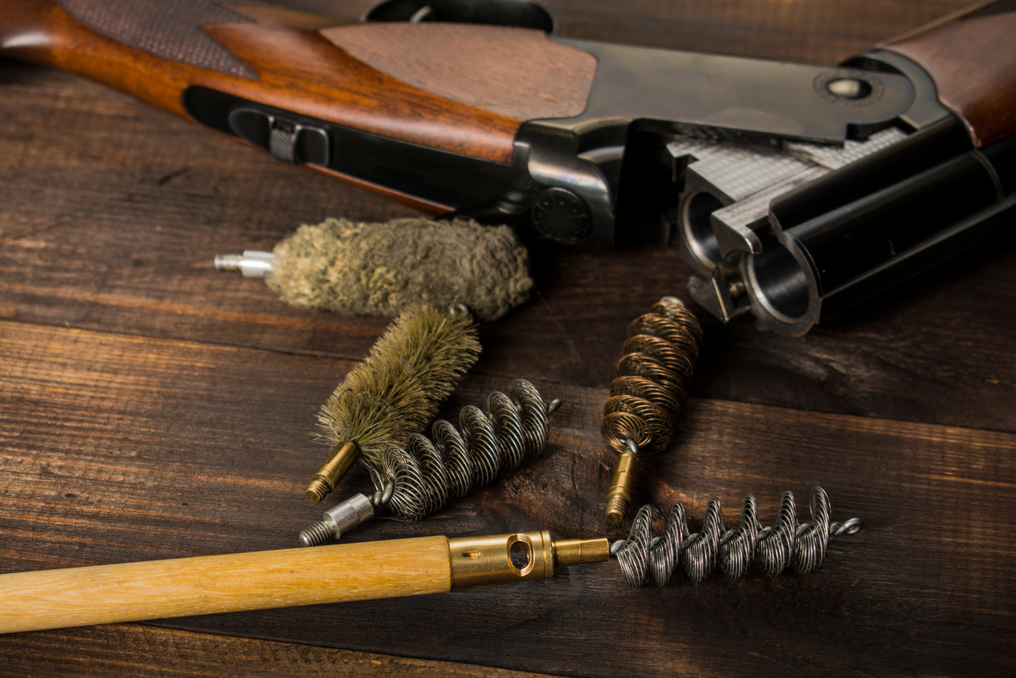Gun cleaning brushes and a rifle on a wooden surface