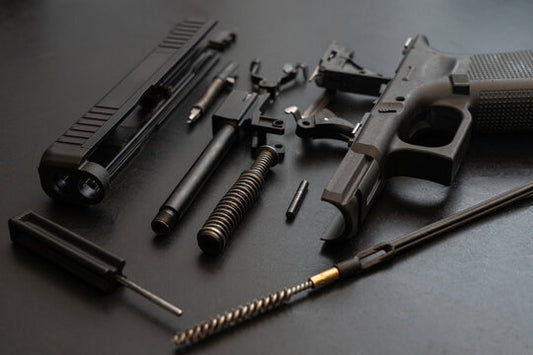 Disassembled gun on a dark surface with various components.