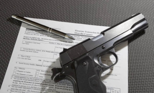 Handgun and firearm transaction form on a gray surface